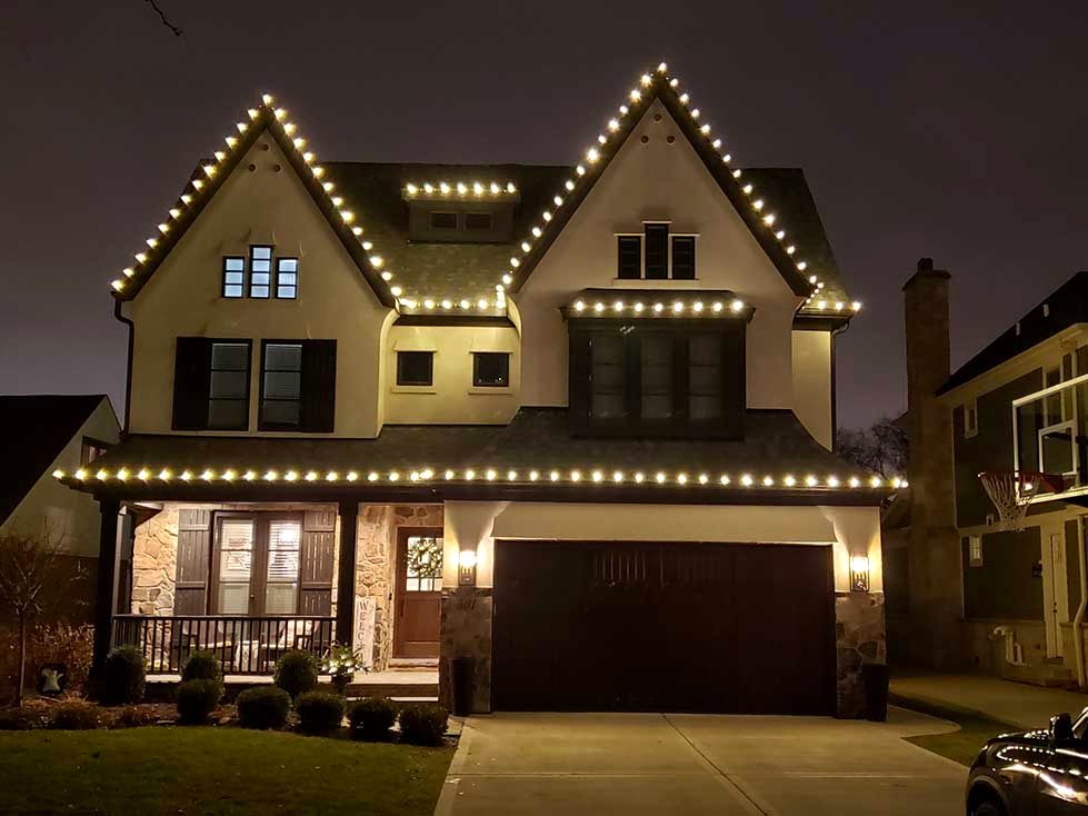 Stunning Christmas light roofline installation on a colonial house at night