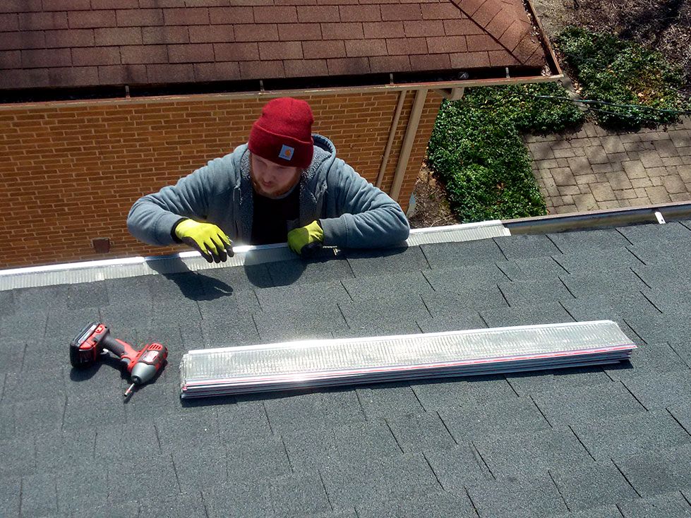 Worker on a heavy duty ladder mounting holiday lights securely